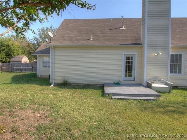 rear view of property featuring a wooden deck and a yard