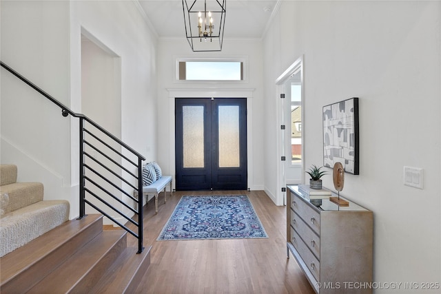 entryway with french doors, ornamental molding, an inviting chandelier, and hardwood / wood-style flooring