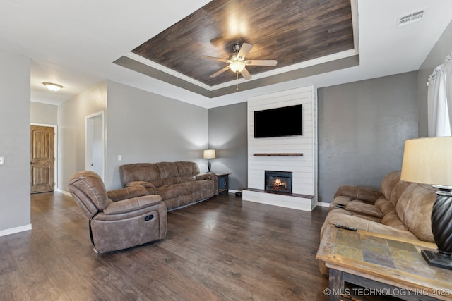 living room with a fireplace, wood ceiling, a raised ceiling, crown molding, and dark wood-type flooring