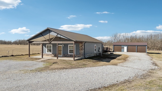 view of front facade with a garage, an outbuilding, and covered porch