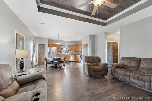 living room featuring crown molding, a tray ceiling, and dark hardwood / wood-style flooring