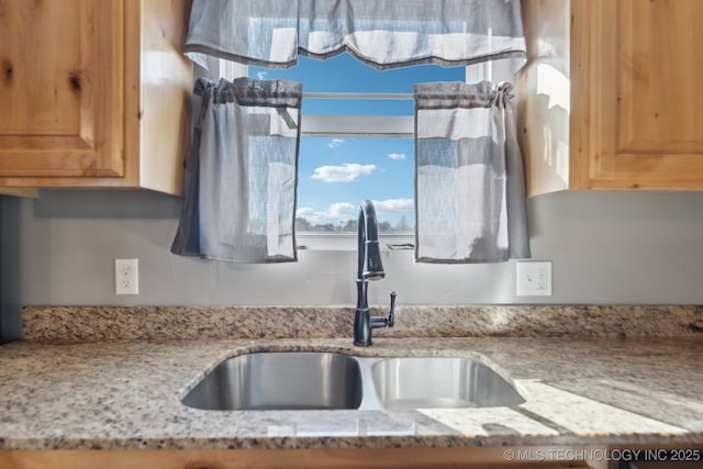 kitchen featuring light stone countertops and sink