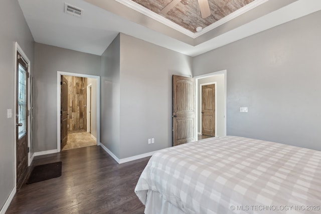 bedroom featuring crown molding, a tray ceiling, and dark hardwood / wood-style floors