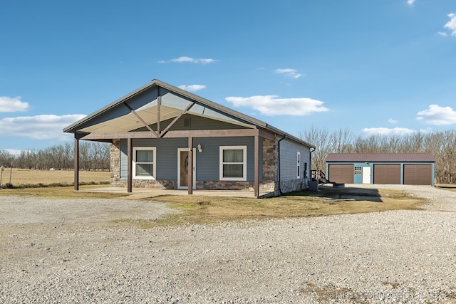 view of front of property featuring a garage, an outdoor structure, and covered porch