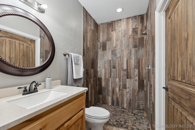 bathroom with vanity, tiled shower, and toilet