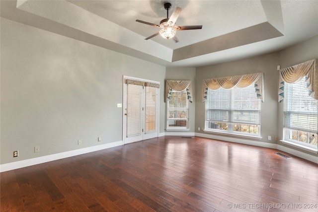 empty room with a tray ceiling, ceiling fan, and hardwood / wood-style floors