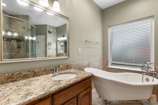 bathroom featuring ceiling fan, plus walk in shower, tile patterned floors, vanity, and tile walls