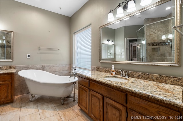 bathroom with tile patterned flooring, shower with separate bathtub, vanity, and tile walls