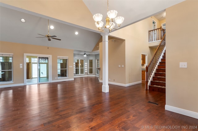 unfurnished living room featuring ceiling fan with notable chandelier, ornate columns, dark wood-type flooring, and high vaulted ceiling