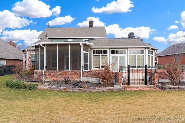 back of property with a sunroom and a lawn