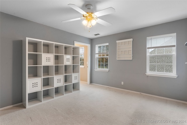 interior space featuring light colored carpet, multiple windows, and ceiling fan