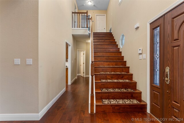 foyer entrance with dark hardwood / wood-style flooring and a towering ceiling