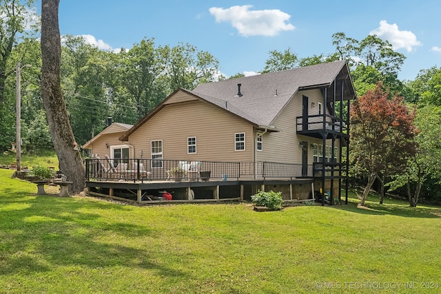 rear view of house featuring a balcony, a yard, and a deck