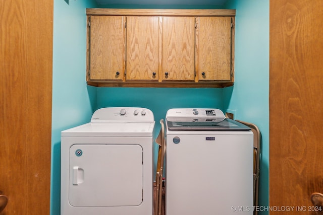 laundry room featuring washer and dryer and cabinets