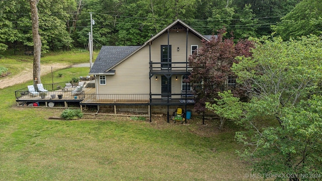 back of property featuring a balcony and a lawn