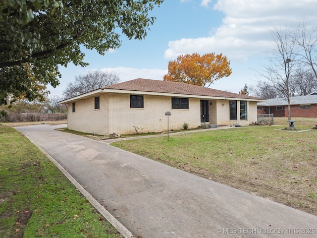 ranch-style home featuring brick siding, a front yard, and fence