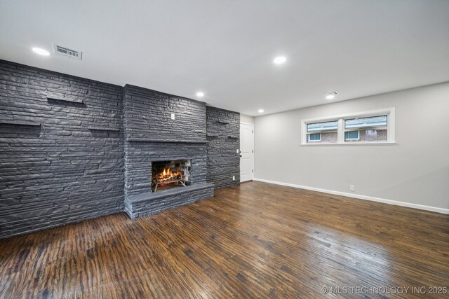 kitchen featuring wall chimney exhaust hood, a breakfast bar area, dark hardwood / wood-style flooring, kitchen peninsula, and a fireplace