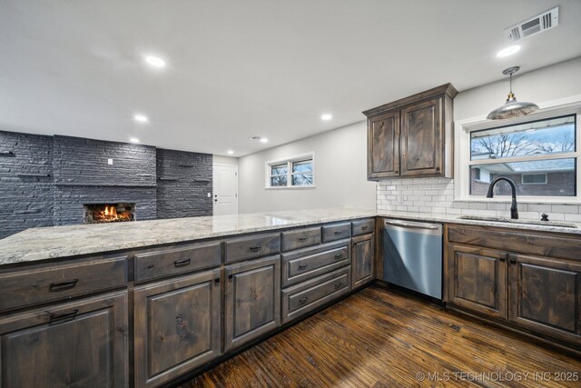 kitchen with sink, premium range hood, light stone counters, decorative light fixtures, and black cooktop