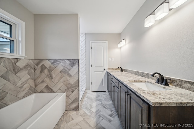 bathroom with vanity, a tub to relax in, and tile walls