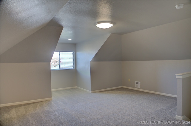 bonus room with light colored carpet, lofted ceiling, and a textured ceiling