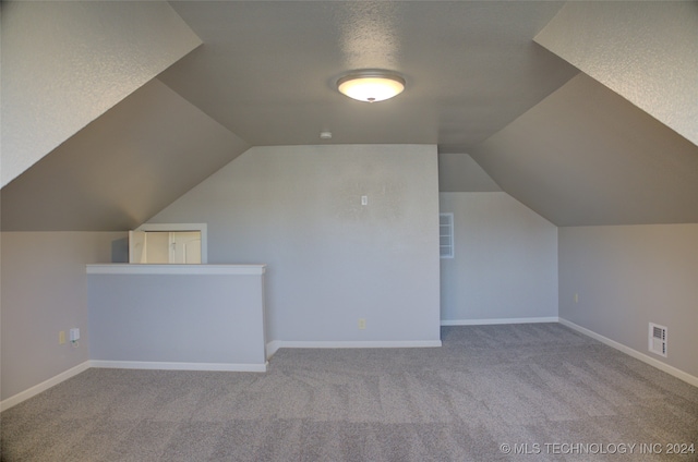 additional living space with light carpet and vaulted ceiling