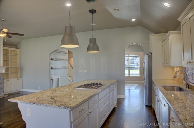 kitchen with sink, vaulted ceiling, light stone countertops, a kitchen island, and stainless steel appliances