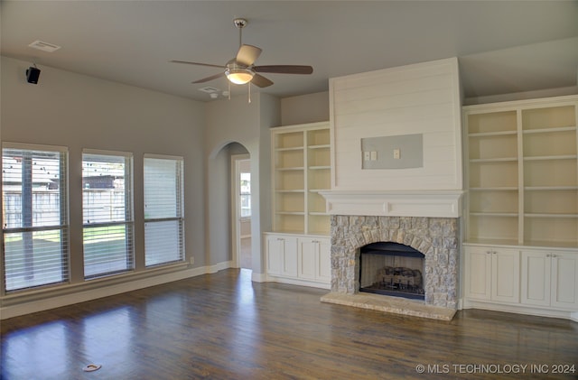 unfurnished living room with a stone fireplace, ceiling fan, and dark hardwood / wood-style floors