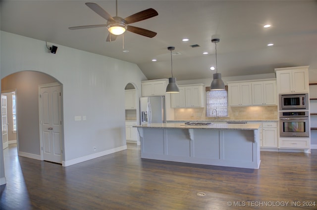 kitchen featuring dark wood-type flooring, stainless steel appliances, white cabinetry, and a center island with sink