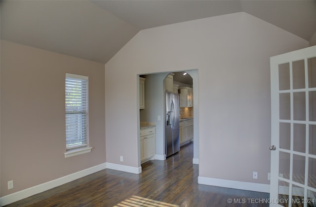 spare room featuring dark hardwood / wood-style floors and lofted ceiling