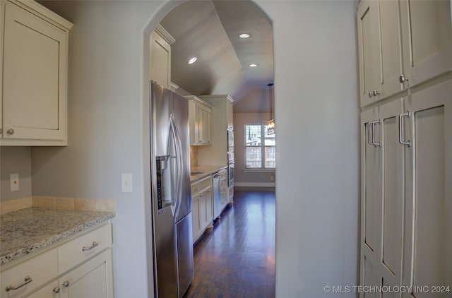 kitchen featuring dark wood-type flooring, stainless steel appliances, light stone counters, a textured ceiling, and lofted ceiling