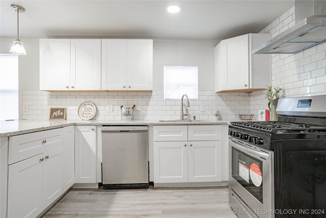 kitchen with appliances with stainless steel finishes, backsplash, wall chimney exhaust hood, sink, and white cabinetry