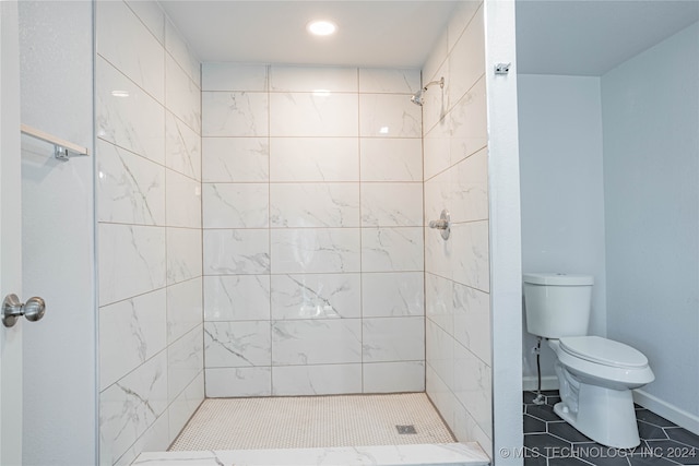 bathroom with tile patterned floors, toilet, and tiled shower