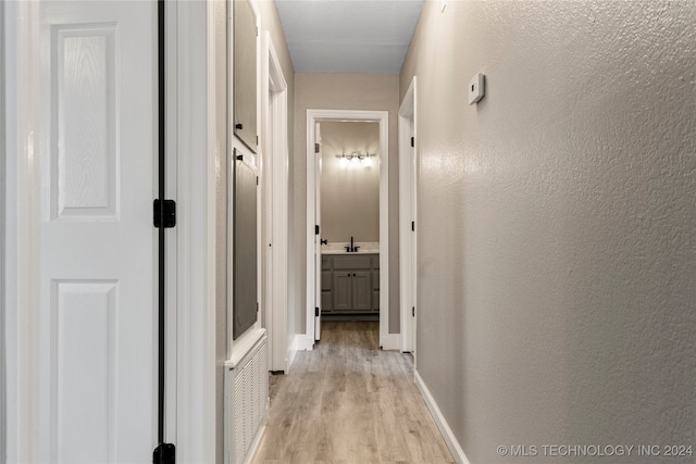 hallway featuring sink and light hardwood / wood-style floors