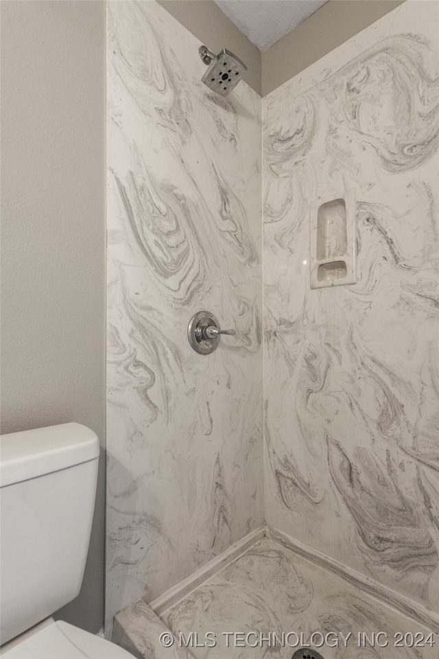 bathroom featuring a tile shower and toilet