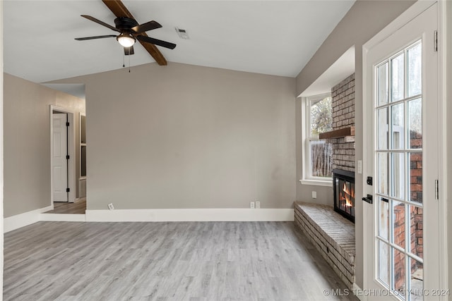 unfurnished living room featuring vaulted ceiling with beams, light hardwood / wood-style flooring, a brick fireplace, and ceiling fan