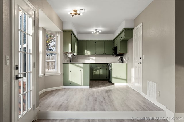 kitchen featuring light hardwood / wood-style flooring, a notable chandelier, backsplash, green cabinetry, and range