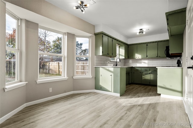 kitchen featuring decorative backsplash, light wood-type flooring, and green cabinetry