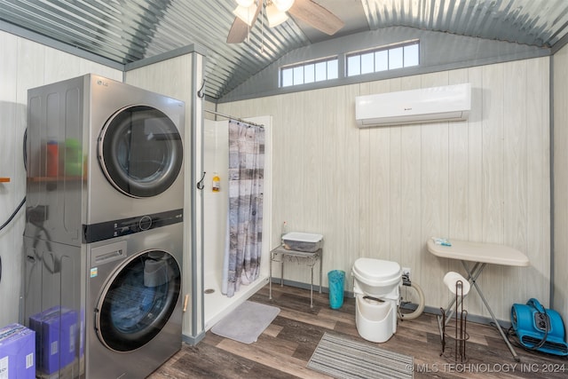 clothes washing area with hardwood / wood-style floors, wooden walls, ceiling fan, stacked washer / dryer, and a wall unit AC