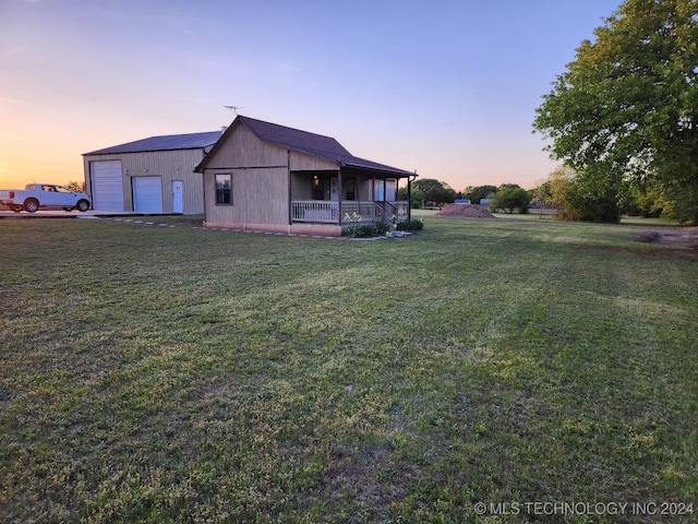 property exterior at dusk with a lawn, an outbuilding, a porch, and a garage