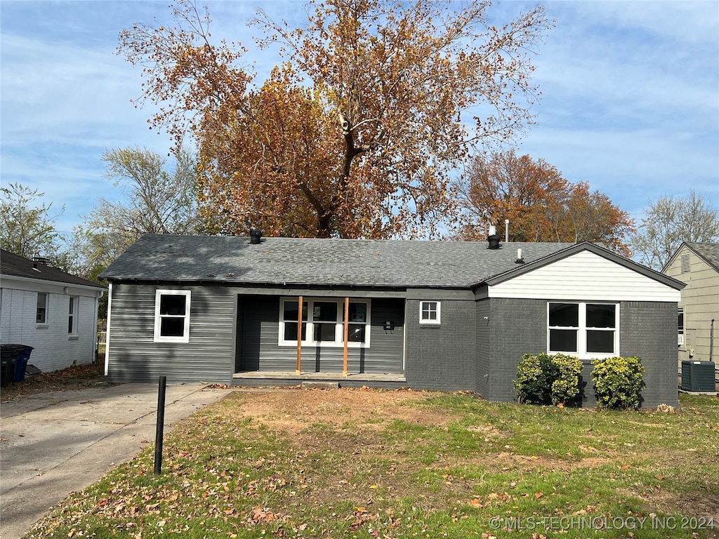 ranch-style home featuring a porch, central air condition unit, and a front lawn