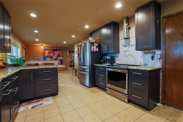 kitchen featuring kitchen peninsula, appliances with stainless steel finishes, backsplash, light stone counters, and light tile patterned floors