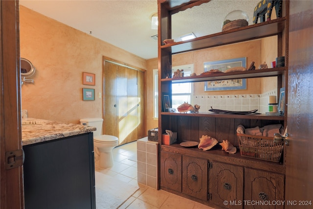 bathroom with backsplash, a textured ceiling, vanity, tile patterned flooring, and toilet