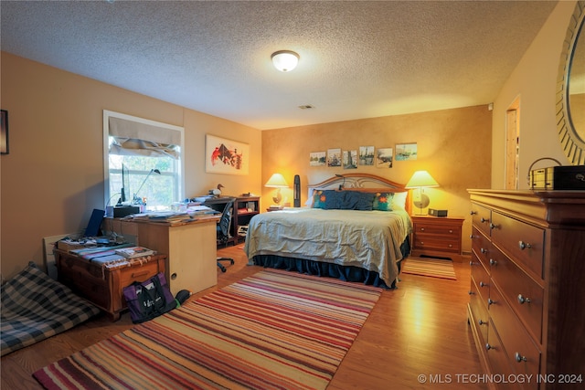 bedroom with light hardwood / wood-style floors and a textured ceiling