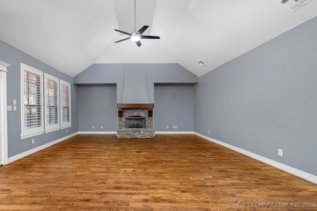 unfurnished living room with hardwood / wood-style flooring, a stone fireplace, ceiling fan, and lofted ceiling