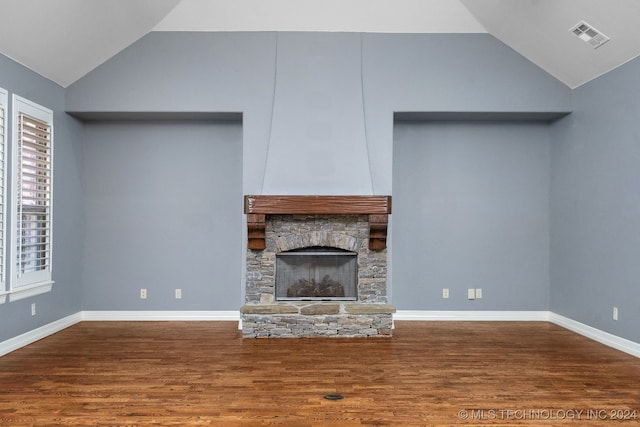 unfurnished living room featuring hardwood / wood-style flooring, a stone fireplace, and vaulted ceiling