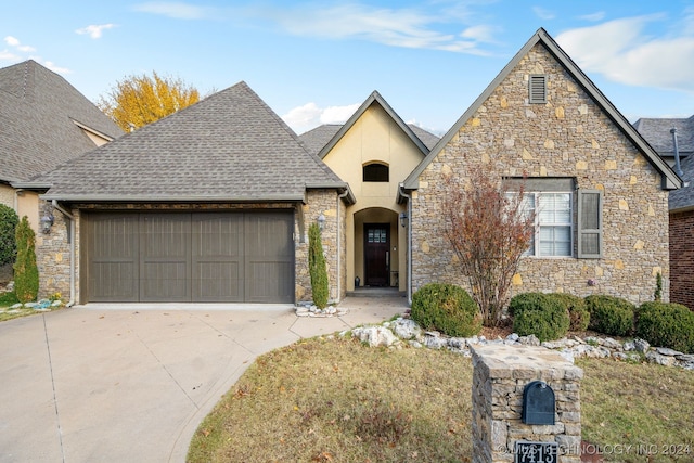 view of front of house featuring an attached garage, a shingled roof, and driveway