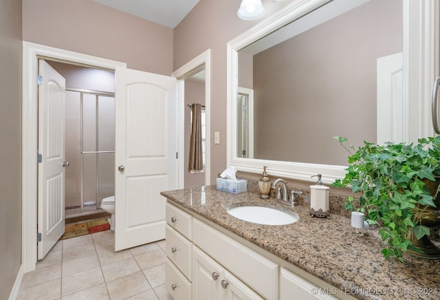 bathroom featuring toilet, a shower with door, vanity, and tile patterned flooring