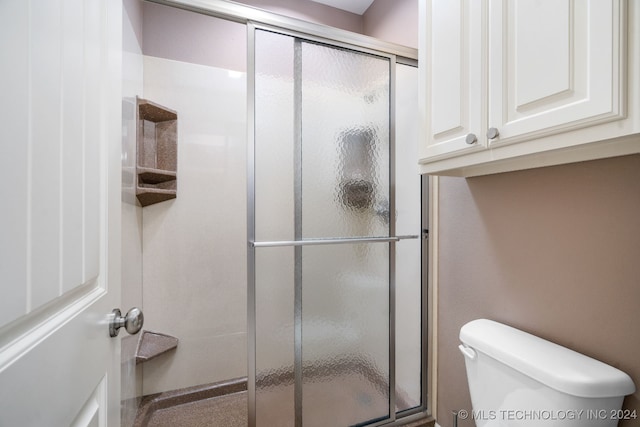 bathroom featuring toilet and a shower with door