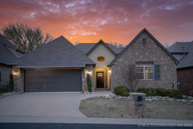 french provincial home featuring stucco siding, driveway, a garage, and roof with shingles