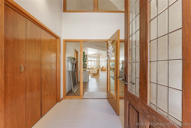 corridor with french doors, a towering ceiling, and light hardwood / wood-style flooring